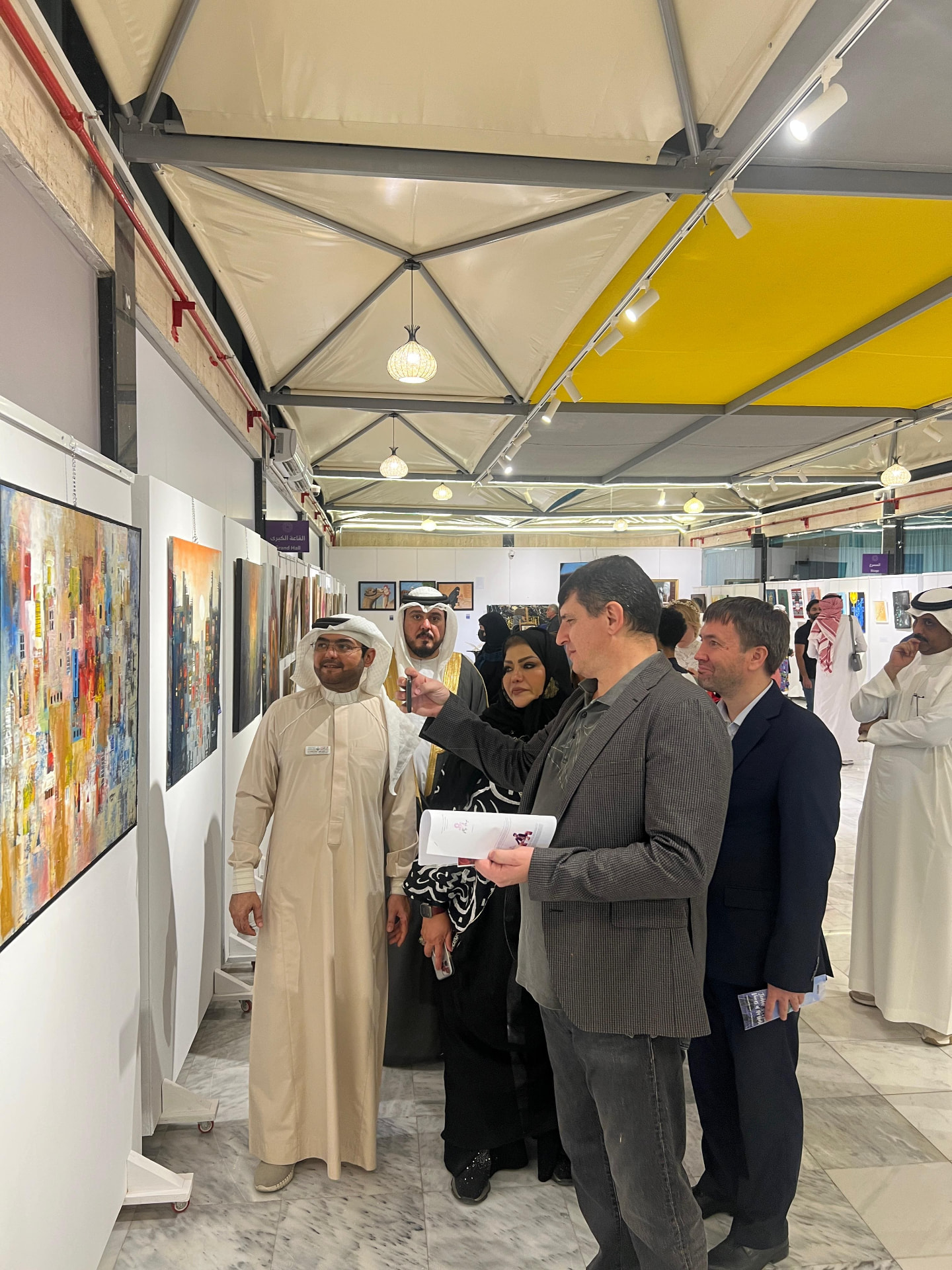 Group portrait of organisers and guests in front of exhibited paintings