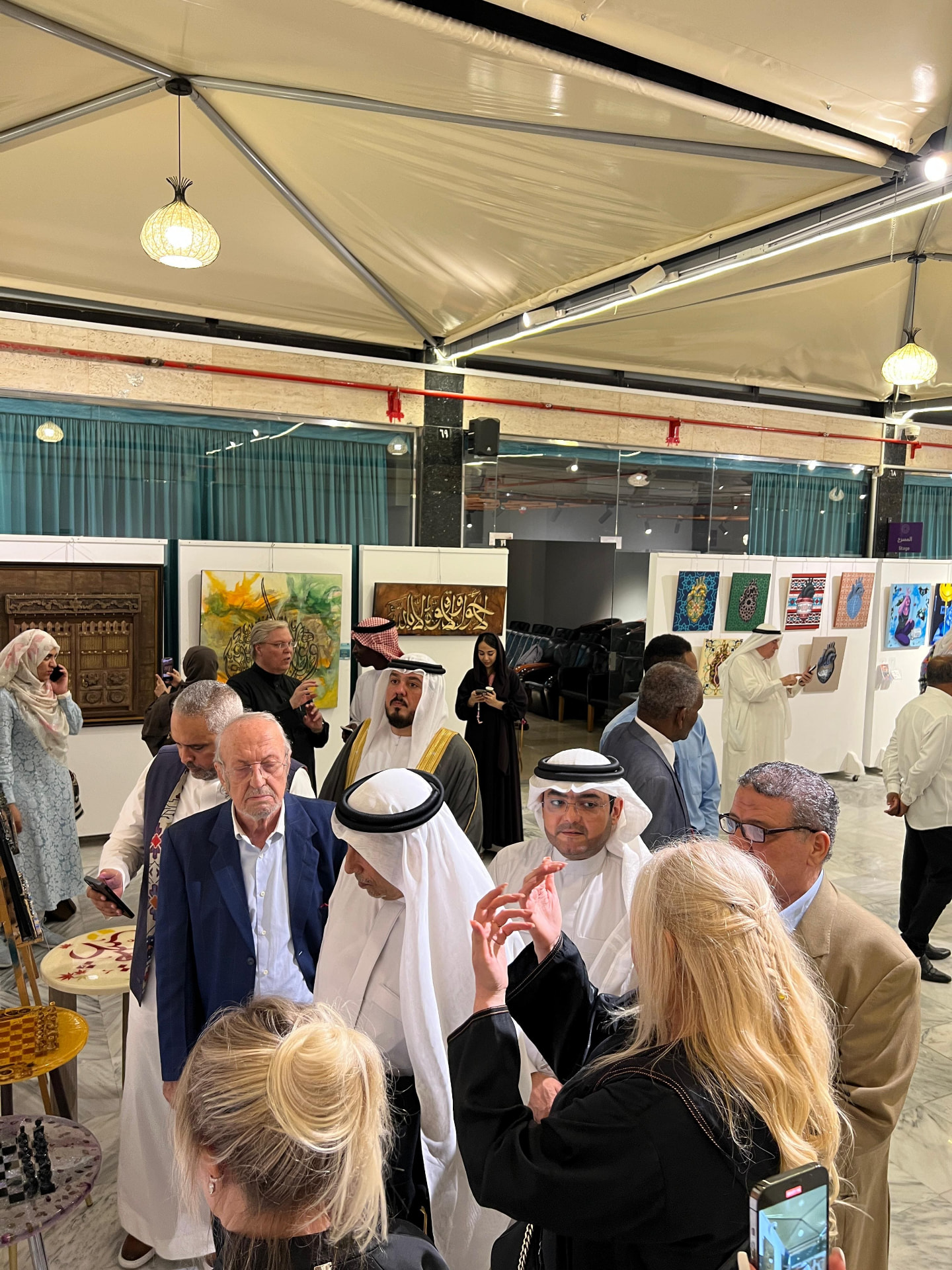 Visitors in the exhibition hall among framed artworks