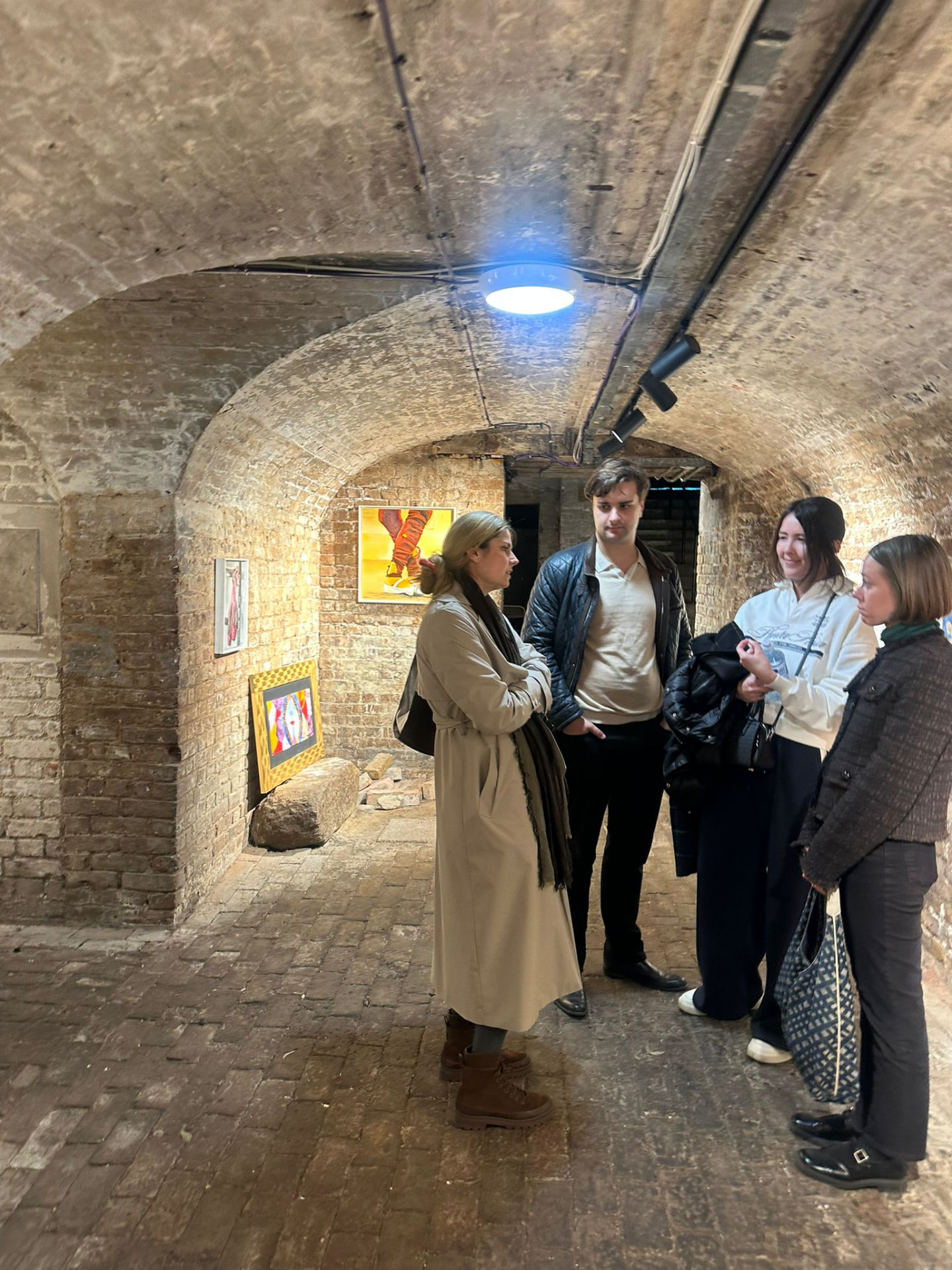Collectors in conversation inside a vaulted brick exhibition space