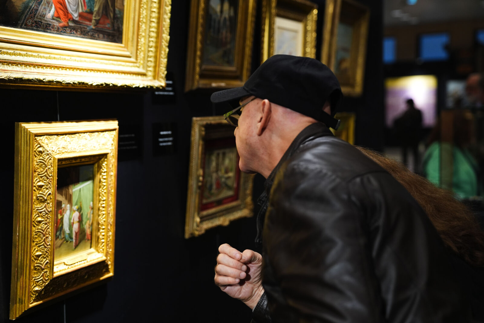 A visitor studying a gilded framed painting at IAAF Istanbul