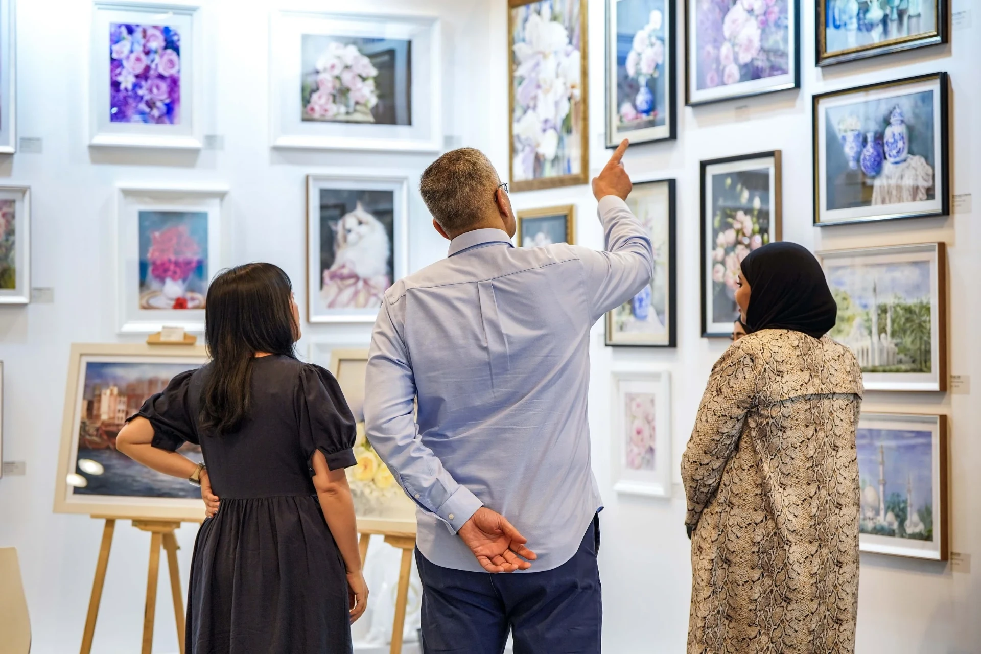 Visitors discussing paintings at World Art Dubai